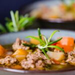 Zuppa toscana fumante servita in una ciotola di ceramica, con verdure fresche e pane tostato.