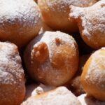 Frittelle di mele dorate e gonfie su un piatto, pronte da gustare.