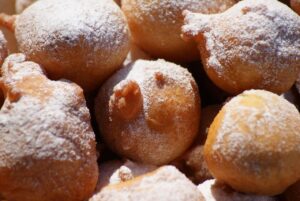 Frittelle di mele dorate e gonfie su un piatto, pronte da gustare.