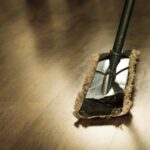 Donna che pulisce un pavimento con ammoniaca, mostrando tecniche di pulizia efficaci.