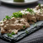Portata di vitello tonnato servita su un piatto con salsa tonnata e capperi.