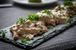 Portata di vitello tonnato servita su un piatto con salsa tonnata e capperi.