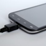 Caricabatterie per telefono collegato alla presa elettrica di notte, illustrando il consumo energetico.