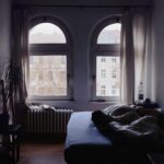 Casa fresca di notte con finestre aperte e tende leggere che filtrano la luce.