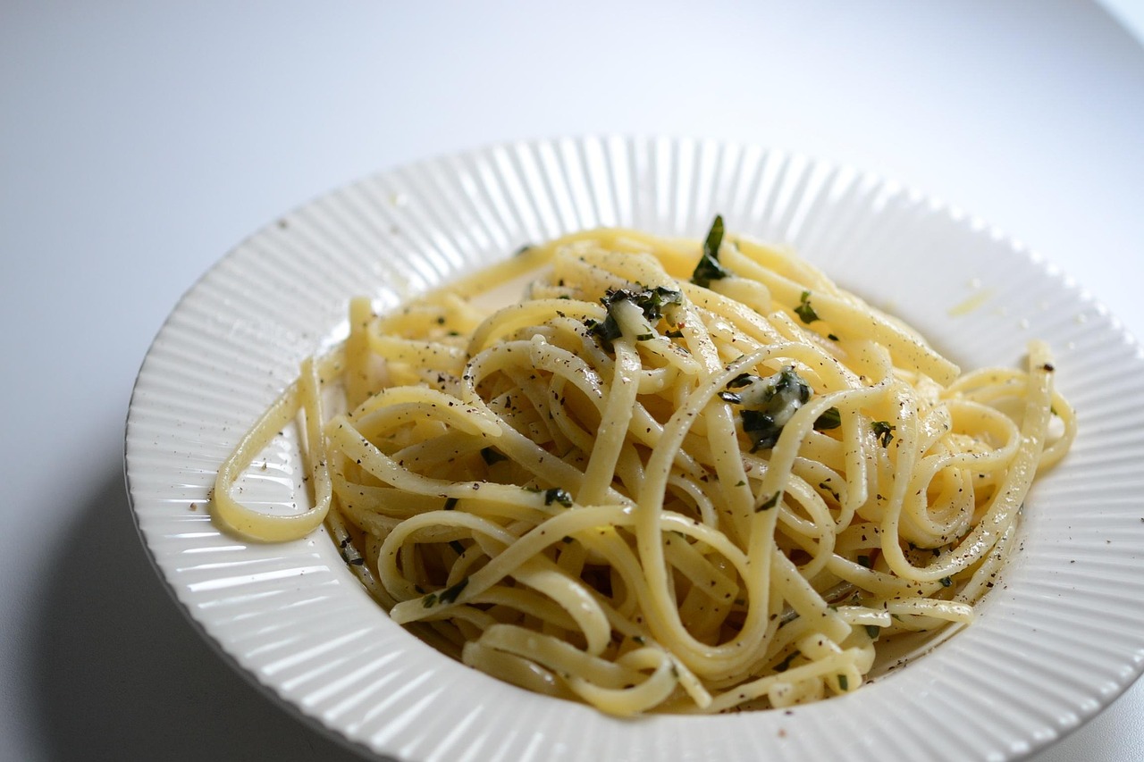 Pasta al limone con crema vellutata, decorata con scorza di limone e foglie di basilico.