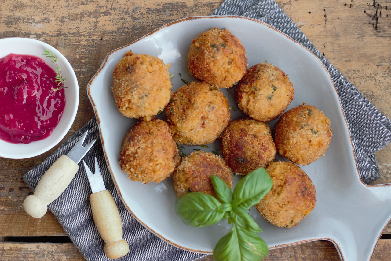 Arancini dorati e croccanti su un piatto, pronti per essere fritti senza aprirsi.